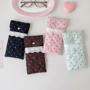 Detail view of quilted polka dot fabric pouches featuring lace trim and heart buttons