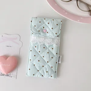 Close-up of a quilted blue polka dot pencil pouch with delicate heart lace trim