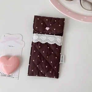 Detailed view of brown quilted storage pouch with white heart lace and pink button