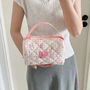 Draagbare gewatteerde roze geruite cosmetische tas met schattige strikpatronen door model.