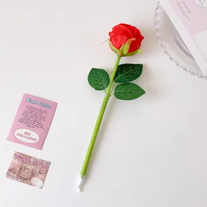 Close-up of a realistic red rose ballpoint pen with green leaves on a clean white desk