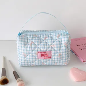 Detail van gewatteerde make-uptas met blauw ruitjespatroon en roze strikjes en handvat