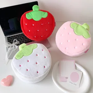 Detail view of cute strawberry-shaped plush cosmetic bags in red, pink, and white