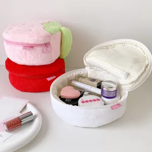 Detail view of open plush strawberry makeup bag showing large capacity for cosmetics