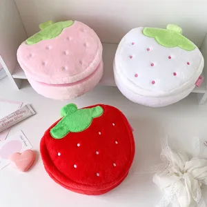Detail shot of three plush strawberry cosmetic bags in red, pink, and white.