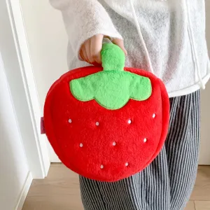 Close-up detail of a cute red strawberry-shaped plush cosmetic bag being held by a hand