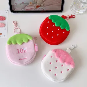 Detailed view of three strawberry-shaped plush coin purses in red, pink, and white