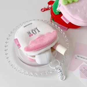 Macro view of cute plush strawberry storage bag with earphone case and lipstick inside
