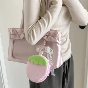 Adorable strawberry plush coin purse charm attached to a pink ruffled satin tote bag