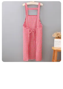 Closeup view of red and white checkered cotton kitchen apron hanging neatly on wall.