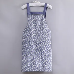 Dettaglio grembiule in tela con motivo floreale spalline blu consistenza cucina