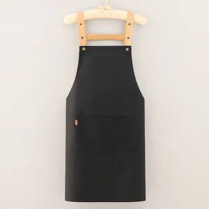 Black cotton twill work apron with brown straps and front pocket for cooking coffee.