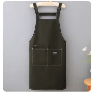 Close-up of dark green canvas apron with durable white stitching and convenient front pockets.