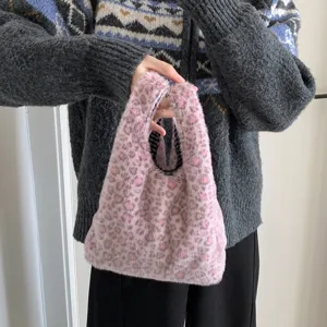 Detailed view of pink leopard print fuzzy handbag carried by a person in a cardigan