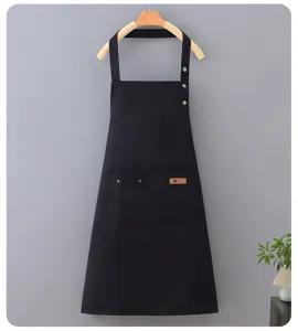 Close-up detail of black work apron showing convenient front pocket and sturdy metal buttons.