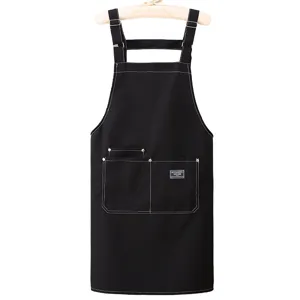 Black canvas apron with cross back straps and utility pockets for kitchen cooking work.
