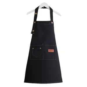 Kids black canvas apron with pockets, adjustable strap and metal buttons for painting.
