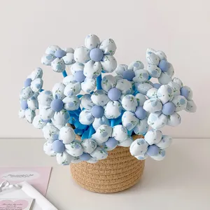 Close-up of fabric flower-topped pens with blue floral patterns in a woven basket