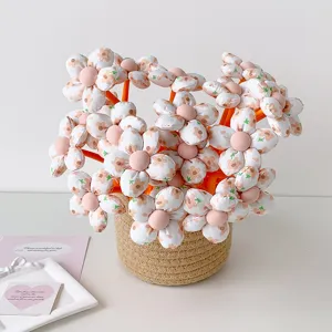 Close-up of plush fabric flower pens arranged in a woven basket for gift giving
