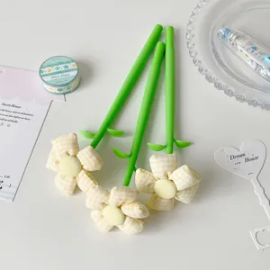 Detailed view of yellow gingham fabric flower topper pens on a minimalist white desk