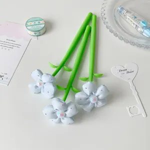 Close-up of three decorative gel pens with light blue fabric flowers and green stems
