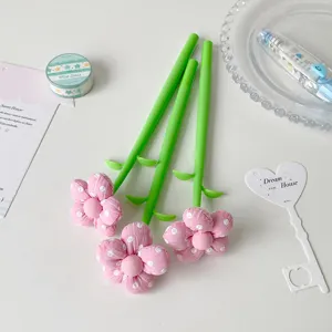 Detail of cute pink fabric flower gel pens with green stem design on white background