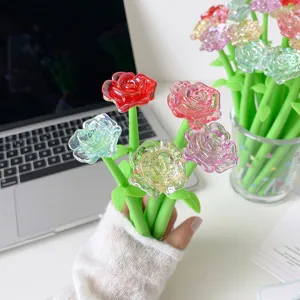 Macro view of colorful crystal rose shaped gel pens held in hand on white desk.