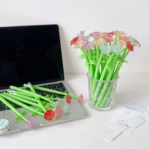 Detailed view of colorful crystal rose gel pens in a glass vase and on a laptop