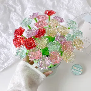 Close-up of colorful crystal-like rose flower pens in a glass vase held by hand