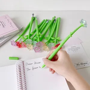 Detailed shot of a hand writing with a creative green rose-shaped crystal gel pen in a notebook