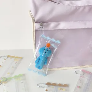 Close-up of clear PVC mini doll storage bag charm with cute blue plush on a backpack