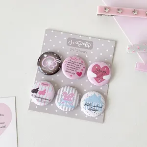 Close-up view of six cute 25mm mini badges with sweet heart and angel designs in pastel pink