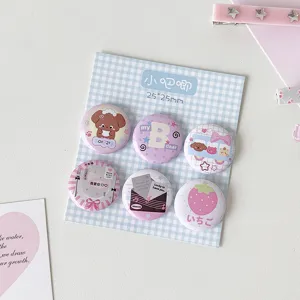 Close-up of six cute 25mm mini cartoon badges displayed on a blue checkered card