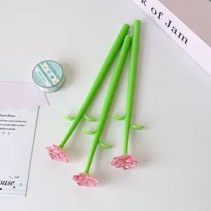 Close-up of creative pink crystal rose pens with green stems on a clean desk.
