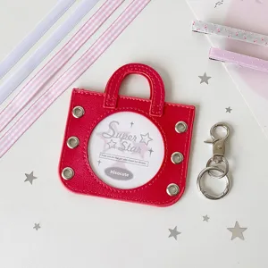 Red handbag-shaped badge holder with a circular display window and metal clasp pendant