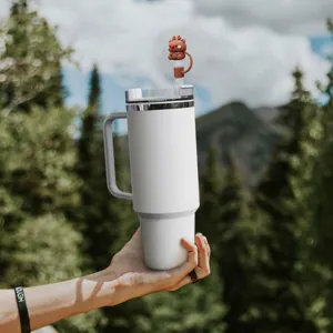 Vue détaillée du gobelet isotherme blanc avec charmant couvre-paille renne en plein air.