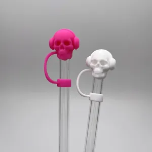 Dettaglio copri cannuccia teschio in silicone rosa e bianco con cannucce trasparenti.