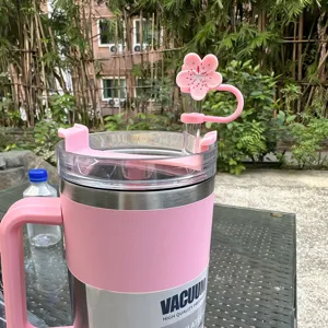Dettaglio tazza isolante rosa con grazioso copristraffa di fiori di ciliegio e cannuccia.