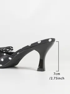 Detail view of stylish black and white polka dot high heel mule with elegant bow design.