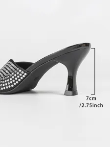Detailopname van zwarte muiltjes met strass en hak, met 7 cm hakhoogte en sprankelende kristallen.