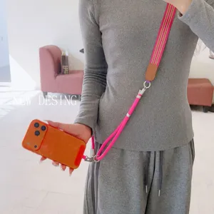 Detail shot of vibrant pink woven phone strap with orange case, metal hardware and leather details.
