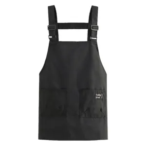 Tablier de travail noir en toile avec doubles bretelles, boucles métalliques et deux poches.