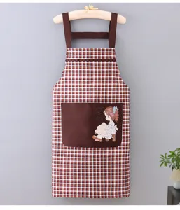 Close-up detail view of the brown plaid kitchen apron featuring a cute girl graphic pocket.