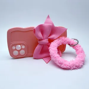 Dettaglio custodia telefono rosa ondulata con grande fiocco in tessuto e morbido braccialetto.