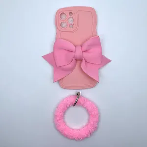Custodia per cellulare in silicone rosa ondulato con grande fiocco in tessuto e cinturino in peluche.