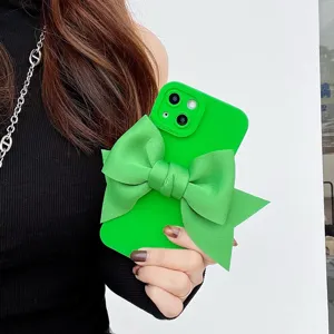 Dettaglio custodia per telefono in silicone verde con grande fiocco in tessuto e protezione.