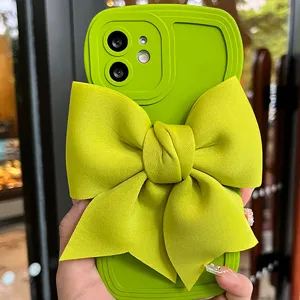 Primo piano di una cover per telefono in silicone verde vivace con grande fiocco in tessuto.