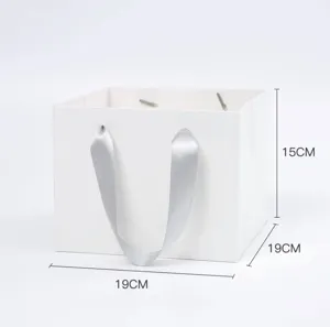 Vista dettagliata della borsa regalo in carta bianca con forma quadrata e manico in nastro.