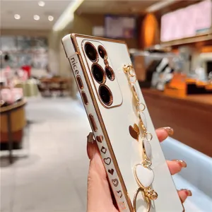 Electroplated heart chain phone case detail view, white soft cover with gold edge and cute strap.