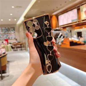 Detailed view of luxury electroplated black phone case with gold edges and lovely heart chain.